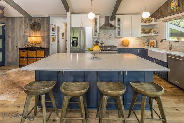 17 Chief Joseph Trl, Big Sky, MT 59716 - kitchen featuring stainless steel appliances, wall chimney range hood, light wood-style flooring, backsplash, and beamed ceiling