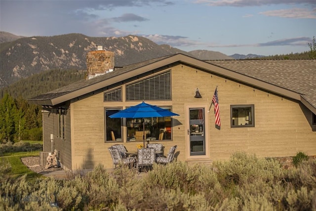 17 Chief Joseph Trl, Big Sky, MT 59716 - rear view of property featuring a mountain view, a chimney, and roof with shingles
