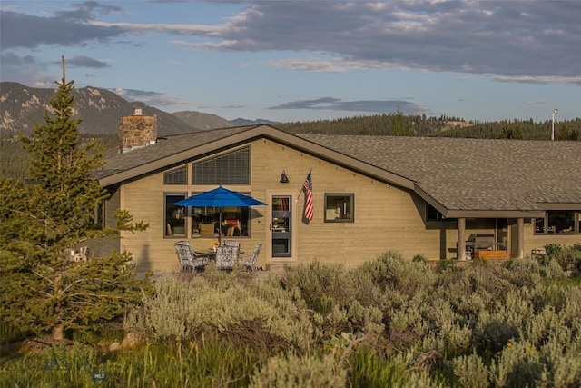 17 Chief Joseph Trl, Big Sky, MT 59716 - rear view of property featuring a chimney, a mountain view, and a shingled roof