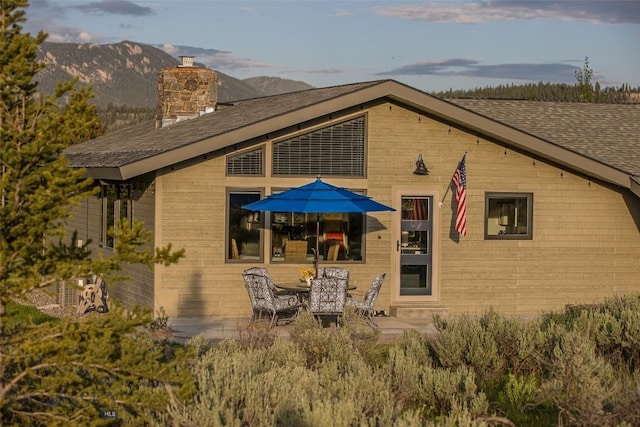 17 Chief Joseph Trl, Big Sky, MT 59716 - back of property with a chimney, a patio, a shingled roof, and a mountain view