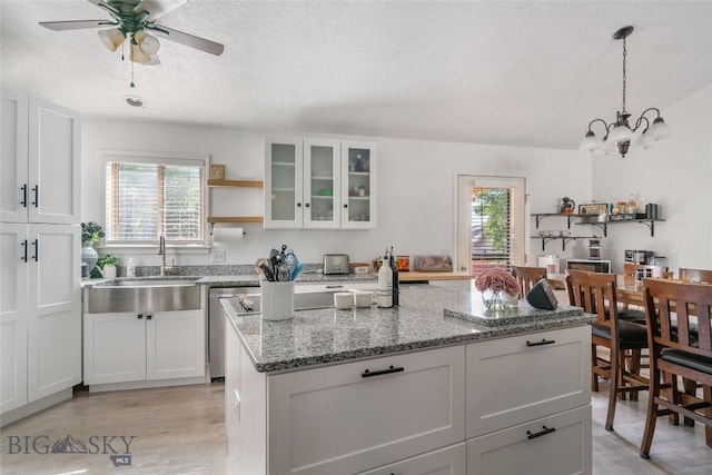 217 Lillian Way, Bozeman, MT 59718 - kitchen featuring light stone countertops, a kitchen island, a chandelier, a textured ceiling, and glass insert cabinets