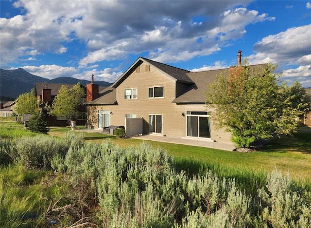 70 Candlelight Meadow Dr, Big Sky, MT 59716 - rear view of house with a patio, a mountain view, a shingled roof, and a chimney
