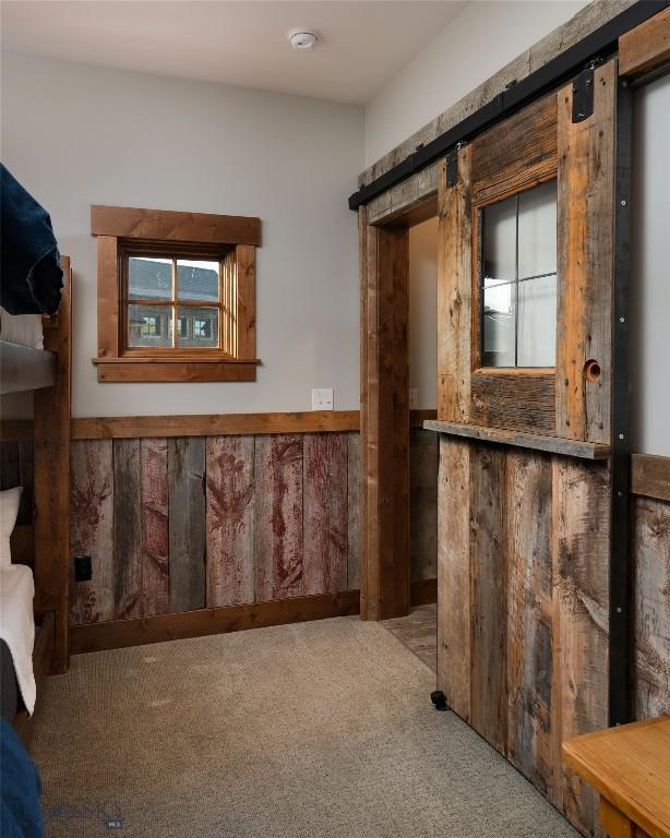 1400 Cottontail Rd, Gallatin Gateway, MT 59730 - interior space featuring carpet floors, wainscoting, a barn door, and wood walls