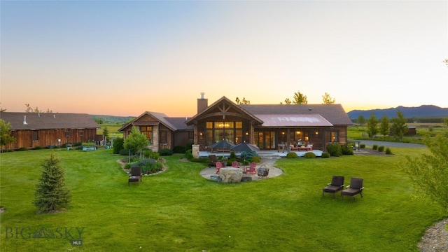 1400 Cottontail Rd, Gallatin Gateway, MT 59730 - back of house featuring a yard, a chimney, a patio area, and a mountain view