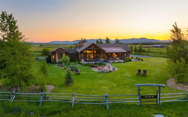 1400 Cottontail Rd, Gallatin Gateway, MT 59730 - back of house at dusk featuring a patio, a mountain view, and a chimney