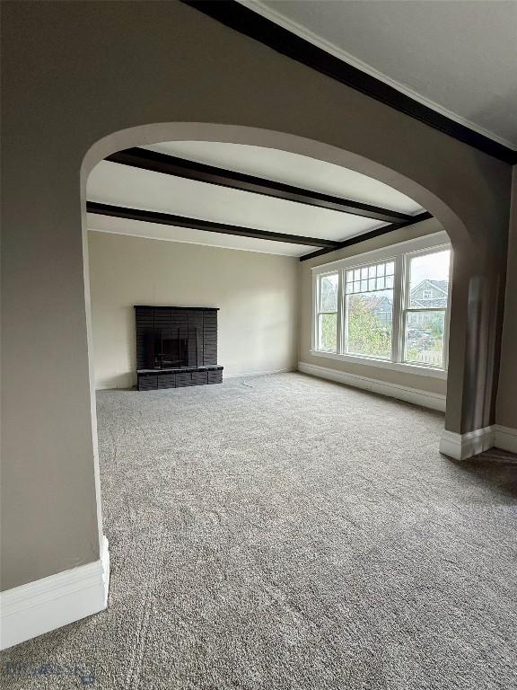 1717 Lowell, Butte, MT 59701 - unfurnished living room featuring carpet floors, a fireplace, arched walkways, beamed ceiling, and crown molding