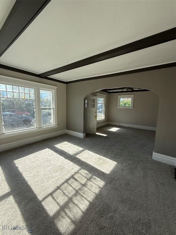 1717 Lowell, Butte, MT 59701 - unfurnished living room featuring arched walkways, carpet floors, and beam ceiling