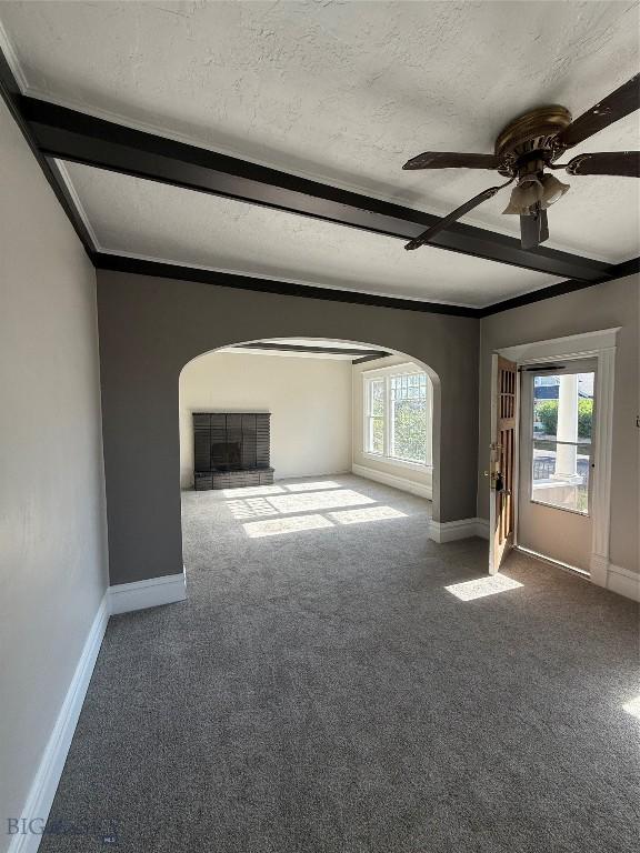 1717 Lowell, Butte, MT 59701 - unfurnished living room featuring arched walkways, carpet floors, a textured ceiling, ceiling fan, and beam ceiling