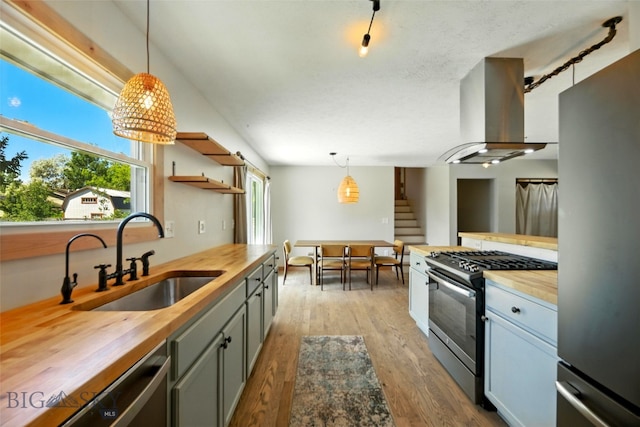 11 N Yellowstone Ave, Bozeman, MT 59718 - kitchen featuring butcher block counters, stainless steel appliances, island range hood, wood finished floors, and decorative light fixtures