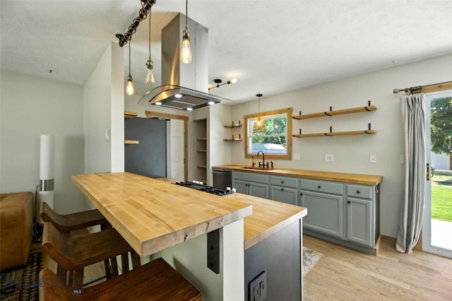 11 N Yellowstone Ave, Bozeman, MT 59718 - kitchen with butcher block countertops, freestanding refrigerator, island exhaust hood, light wood finished floors, and open shelves