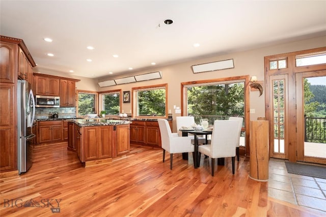 11540 Taiga Trl, Bozeman, MT 59715 - kitchen with stainless steel appliances, light wood-type flooring, brown cabinetry, recessed lighting, and a kitchen island