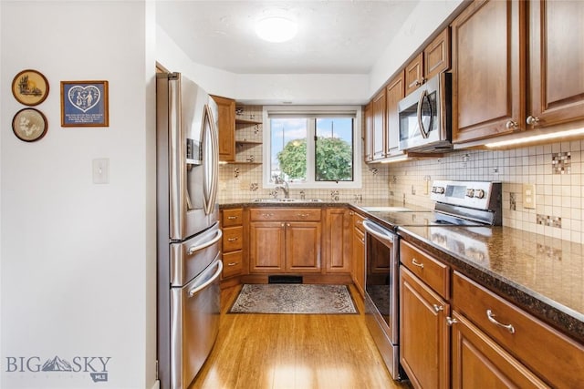 1406 Gilman Ave, Butte, MT 59701 - kitchen with appliances with stainless steel finishes, light wood finished floors, brown cabinetry, decorative backsplash, and dark stone countertops