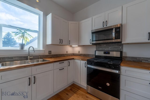 416 N 3rd St, Livingston, MT 59047 - kitchen featuring butcher block countertops, appliances with stainless steel finishes, decorative backsplash, and white cabinets