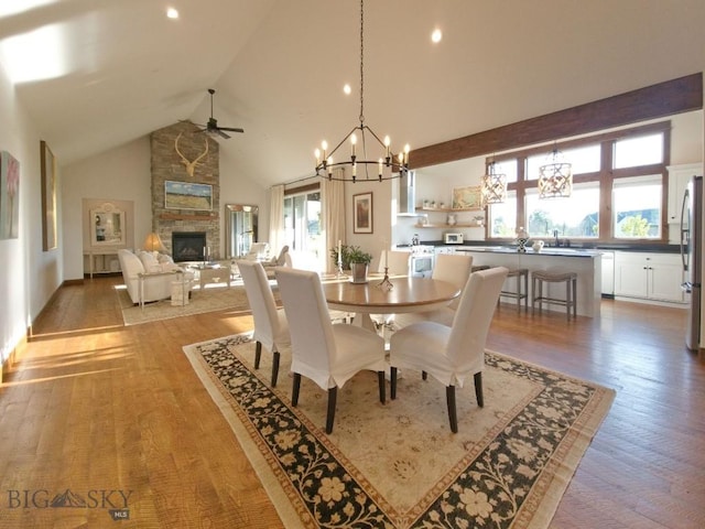 243 Tinkers Ln, Bozeman, MT 59718 - dining space with a chandelier, a stone fireplace, ceiling fan, high vaulted ceiling, and healthy amount of natural light