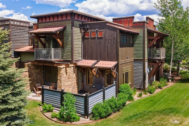 99 Pheasant Tail Ln Unit 1, Big Sky, MT 59716 - view of side of property featuring a balcony, a lawn, and stone siding