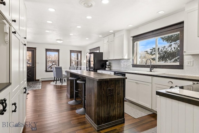 12977 Cottonwood Rd, Bozeman, MT 59718 - kitchen with freestanding refrigerator, recessed lighting, white cabinetry, backsplash, and a breakfast bar