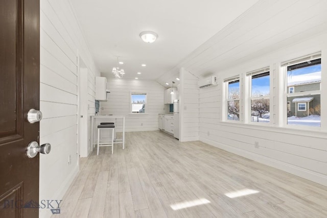12977 Cottonwood Rd, Bozeman, MT 59718 - unfurnished living room with light wood finished floors, an AC wall unit, wooden walls, and plenty of natural light