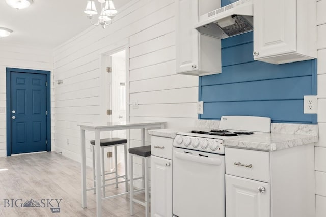 12977 Cottonwood Rd, Bozeman, MT 59718 - kitchen featuring white electric stove, under cabinet range hood, white cabinets, light wood-style floors, and wooden walls
