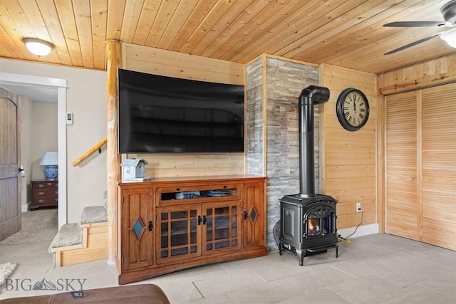 185 Peak, Bozeman, MT 59715 - living room with wooden ceiling, wooden walls, a wood stove, a ceiling fan, and tile patterned flooring