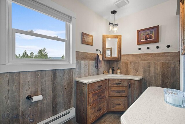 185 Peak, Bozeman, MT 59715 - bathroom with a wainscoted wall, wooden walls, vanity, a baseboard radiator, and wood finished floors
