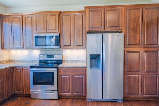 3230 S 26th Ave, Bozeman, MT 59718 - kitchen with stainless steel appliances, light stone counters, dark wood finished floors, and brown cabinets
