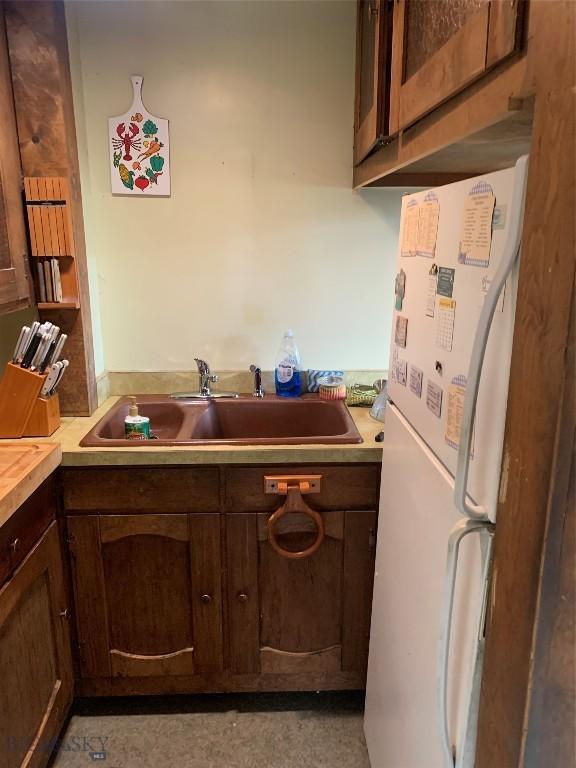 1813 Adams Ave, Butte, MT 59701 - kitchen with freestanding refrigerator, light countertops, and dark brown cabinets