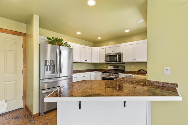 901 Floyd Way, Livingston, MT 59047 - kitchen with stainless steel appliances, a peninsula, white cabinets, a kitchen breakfast bar, and recessed lighting