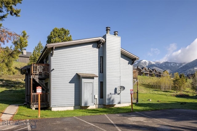 139 Spruce Cone Dr Unit 14, Big Sky, MT 59716 - back of property featuring a chimney, a mountain view, uncovered parking, and a yard