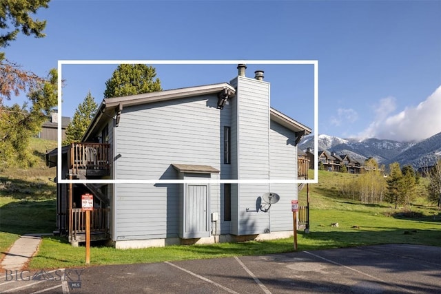 139 Spruce Cone Dr Unit 14, Big Sky, MT 59716 - view of side of property with a chimney, a mountain view, a lawn, uncovered parking, and a balcony
