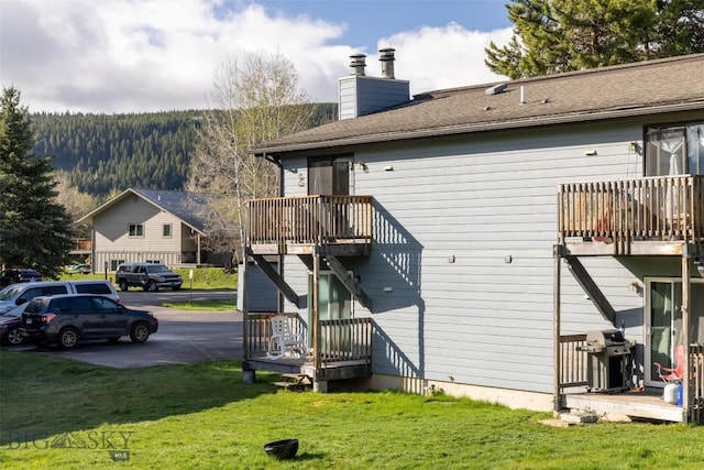 139 Spruce Cone Dr Unit 14, Big Sky, MT 59716 - rear view of house featuring a balcony, a chimney, and a yard