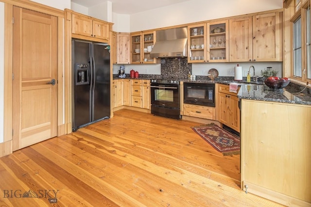 2500 Little Coyote Rd Unit 34, Big Sky, MT 59716 - kitchen with black appliances, wall chimney exhaust hood, light brown cabinetry, light wood-type flooring, and dark stone counters
