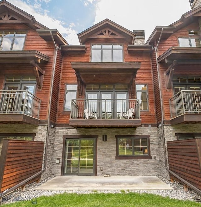 2500 Little Coyote Rd Unit 34, Big Sky, MT 59716 - rear view of property with a balcony, stone siding, a chimney, and a patio