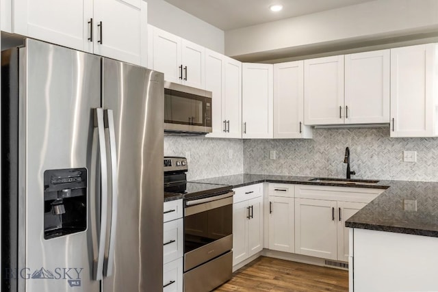 6707 Blackwood Rd Unit C, Bozeman, MT 59715 - kitchen featuring appliances with stainless steel finishes, white cabinets, dark stone countertops, tasteful backsplash, and recessed lighting