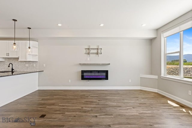 6707 Blackwood Rd Unit C, Bozeman, MT 59715 - unfurnished living room with dark wood-style floors, recessed lighting, a glass covered fireplace, a mountain view, and heating unit