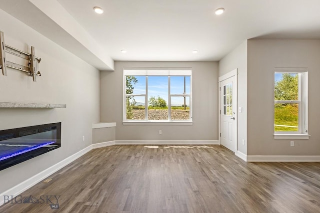 6707 Blackwood Rd Unit C, Bozeman, MT 59715 - unfurnished living room with wood finished floors, healthy amount of natural light, a glass covered fireplace, and recessed lighting