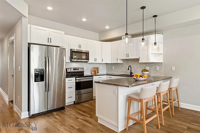 6707 Blackwood Rd Unit C, Bozeman, MT 59715 - kitchen with stainless steel appliances, a peninsula, dark countertops, wood finished floors, and recessed lighting