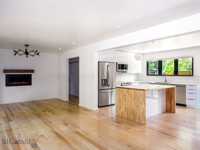1206 N Cedarview Dr, Bozeman, MT 59715 - kitchen featuring appliances with stainless steel finishes, a kitchen island, backsplash, modern cabinets, and a lit fireplace