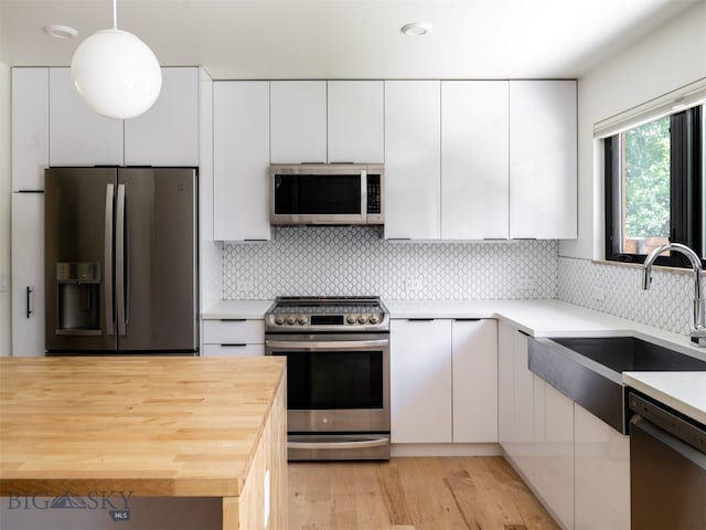 1206 N Cedarview Dr, Bozeman, MT 59715 - kitchen with stainless steel appliances, wood counters, white cabinetry, light wood-type flooring, and tasteful backsplash