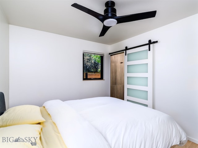 1206 N Cedarview Dr, Bozeman, MT 59715 - bedroom featuring a barn door, ceiling fan, and wood finished floors