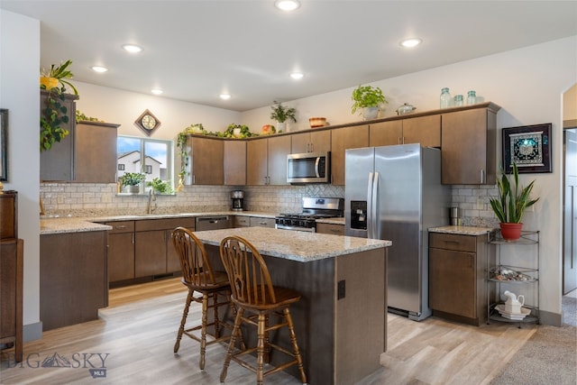 1308 Scooter Ln, Belgrade, MT 59714 - kitchen with stainless steel appliances, light wood finished floors, tasteful backsplash, a kitchen island, and recessed lighting
