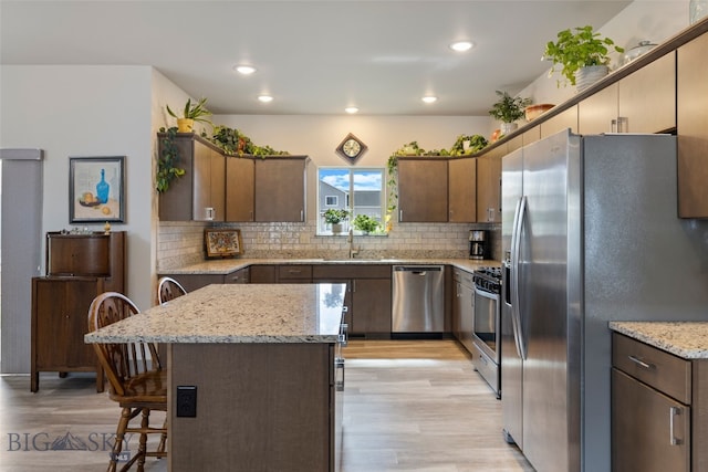 1308 Scooter Ln, Belgrade, MT 59714 - kitchen featuring stainless steel appliances, light wood-style flooring, tasteful backsplash, recessed lighting, and a breakfast bar area