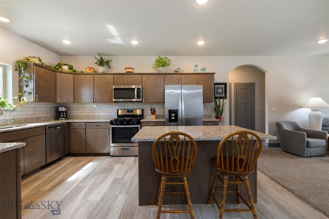 1308 Scooter Ln, Belgrade, MT 59714 - kitchen with appliances with stainless steel finishes, arched walkways, tasteful backsplash, a center island, and recessed lighting