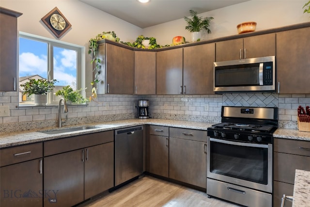 1308 Scooter Ln, Belgrade, MT 59714 - kitchen with stainless steel appliances, light wood-type flooring, backsplash, light stone countertops, and dark brown cabinets