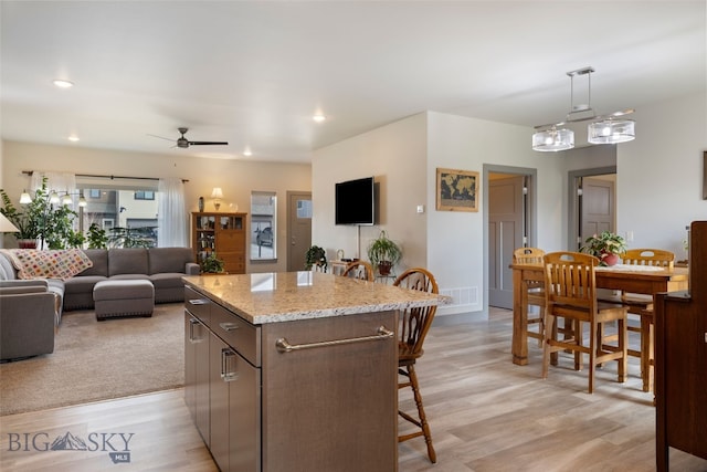 1308 Scooter Ln, Belgrade, MT 59714 - kitchen with a kitchen breakfast bar, open floor plan, a ceiling fan, a kitchen island, and light wood-style flooring
