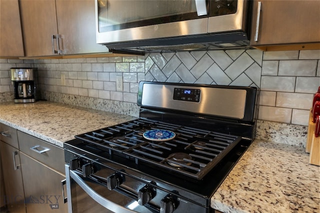 1308 Scooter Ln, Belgrade, MT 59714 - kitchen view of stainless steel appliances, backsplash, and light stone countertops