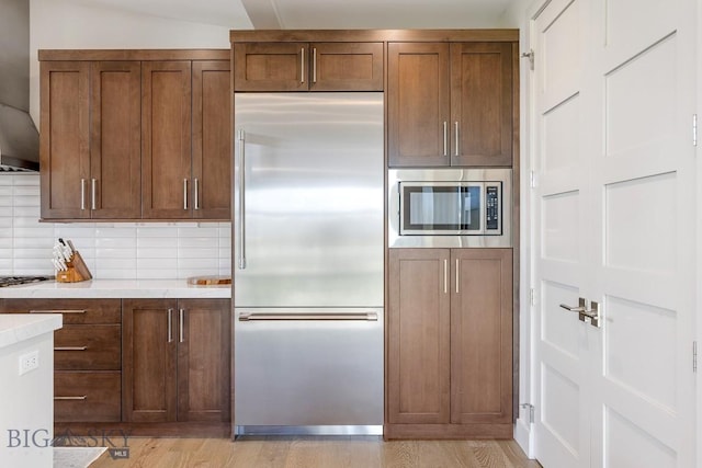 20 Caymus Ln Unit D, Bozeman, MT 59718 - kitchen with built in appliances, light countertops, decorative backsplash, and light wood finished floors