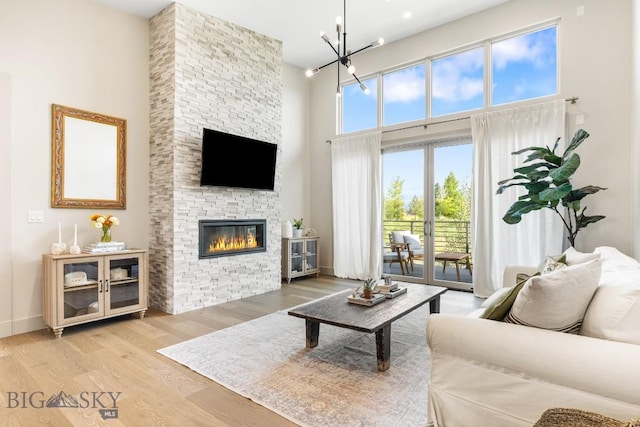 20 Caymus Ln Unit D, Bozeman, MT 59718 - living room featuring a high ceiling, wood finished floors, a stone fireplace, and a chandelier