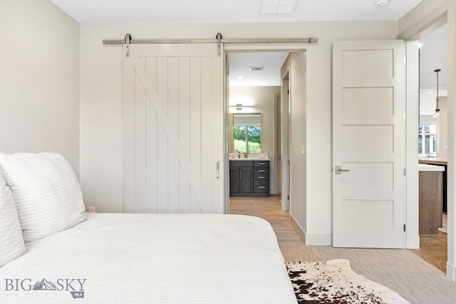 20 Caymus Ln Unit D, Bozeman, MT 59718 - bedroom with connected bathroom, a barn door, and light wood-type flooring