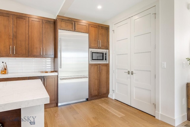 20 Caymus Ln Unit D, Bozeman, MT 59718 - kitchen featuring built in appliances, brown cabinetry, light wood-type flooring, backsplash, and recessed lighting