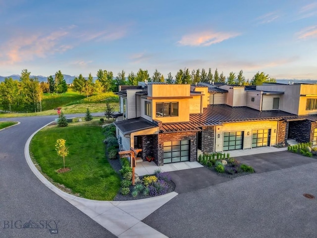 20 Caymus Ln Unit D, Bozeman, MT 59718 - contemporary house featuring a standing seam roof, driveway, stone siding, an attached garage, and a metal roof